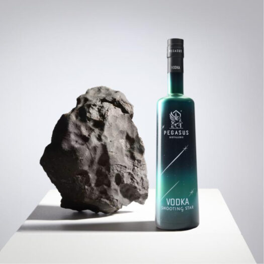 A bottle of shooting star vodka next to a meteorite